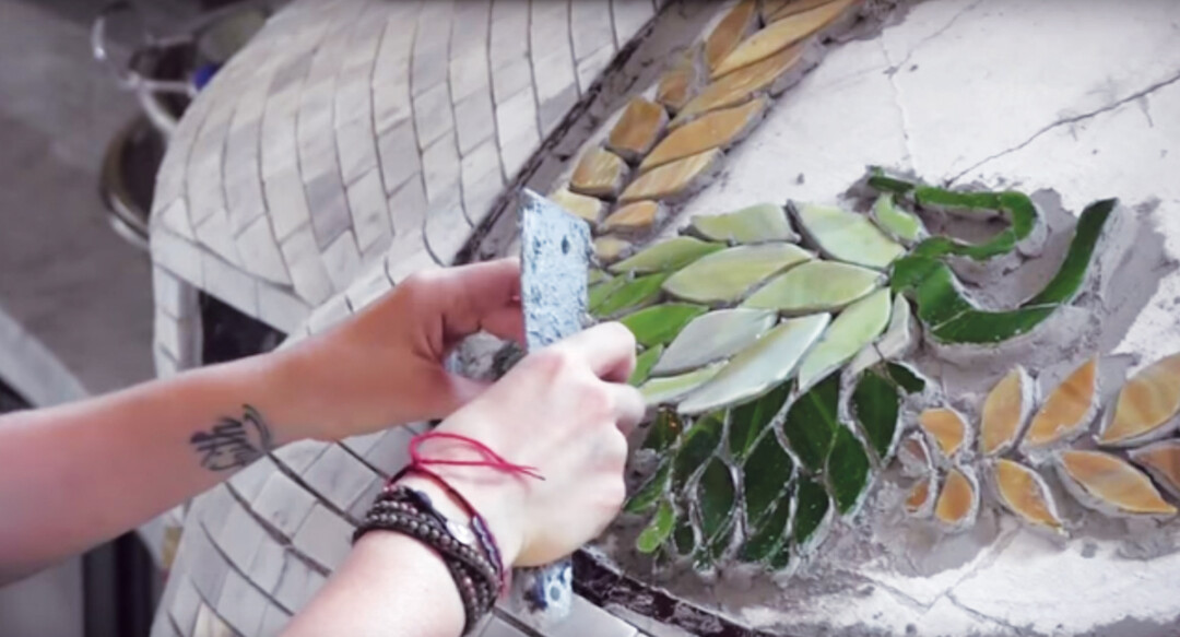 Celeste Sullivan hand-places glass pieces on the mosaic