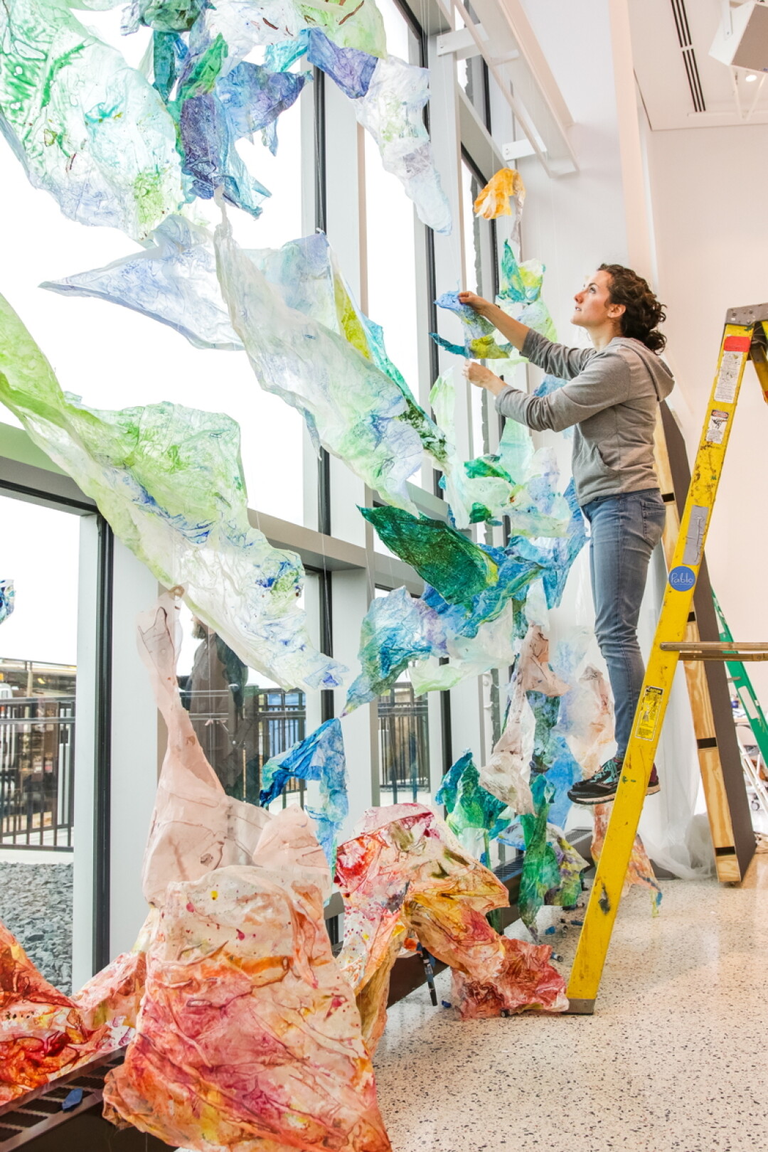 JUST HANGIN’ AT THE PABLO. Artist Holli Jacobson installs part of “NOW: Emerging Artists of the Chippewa Valley,” a new exhibit that runs through July 12 at the Pablo Center at the Confluence.