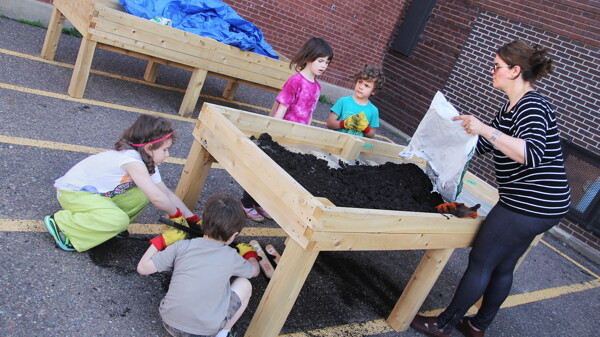 DOWN AND DIRTY. Students from the Chippewa Valley Montessori Charter School in Eau Claire help prepare raised garden beds for planting.