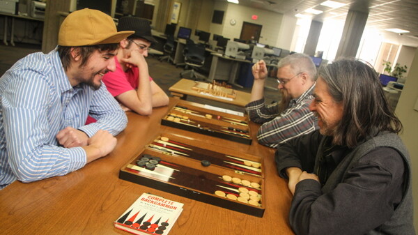 IT AIN’T CHECKERS. Clockwise from upper right, Hans Kishel and Paul Kaldjian (both of whom are tournament organizers) and UW-Eau Claire students Adam Gross and Jordan Niles practice backgammon in advance of the Backgammon City Championship at UWEC’s McIntyre Library.
