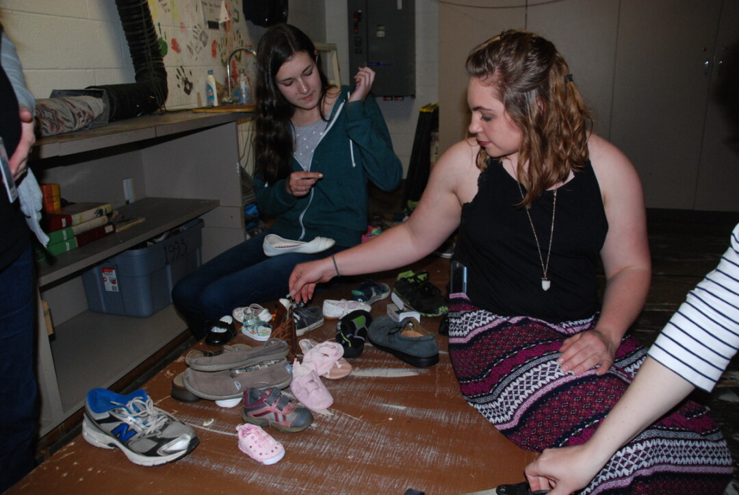 TALK ABOUT SOLE. Memorial High School students Sarah Schiefelbein, left, and Kaylee Winsand prepare an art installation that will be part of the Migrations project.